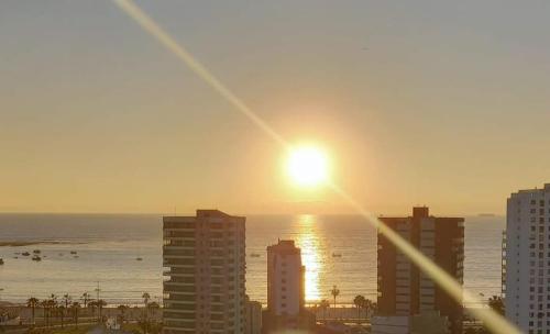 a sunset over a city with the ocean and buildings at Alojamiento Costazul2 in Iquique