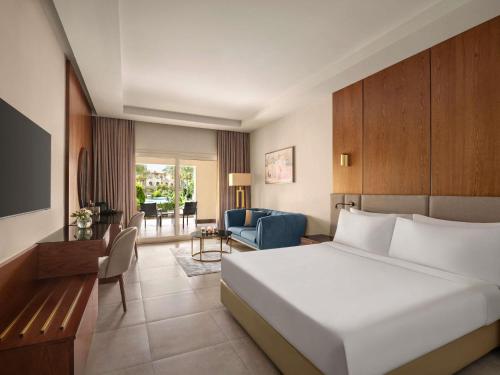 a bedroom with a bed and a living room at Mövenpick Hotel Cairo - Media City in 6th Of October