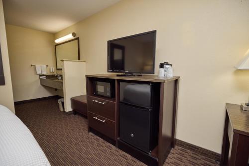 クラマスフォールズにあるCimarron Inn Klamath Fallsのドレッサーの上に薄型テレビがあるホテルの部屋