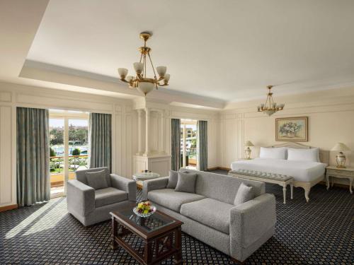 a hotel room with a bed and a couch and chairs at Mövenpick Hotel Cairo - Media City in 6th Of October