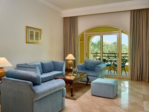 a living room with blue furniture and a balcony at Mövenpick Hotel Cairo - Media City in 6th Of October