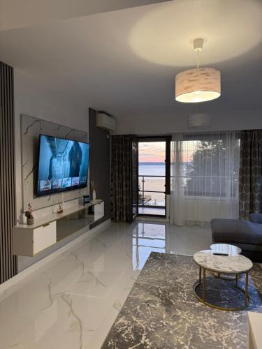 een woonkamer met een tv, een bank en een tafel bij Elegance Apartament in Mamaia