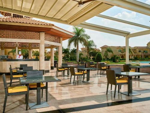 a patio with tables and chairs and a pool at Mövenpick Hotel Cairo - Media City in 6th Of October