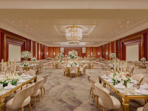 a banquet hall with tables and chairs and a chandelier at Mövenpick Hotel Cairo - Media City in 6th Of October