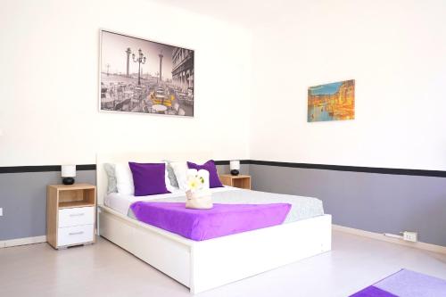 a bedroom with a white bed with a purple blanket at Arco Iris Locazioni turistiche in Mestre