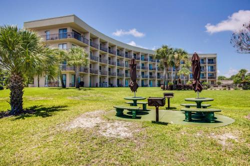 a hotel with picnic tables and umbrellas in a park at Pirates Bay B314 in Fort Walton Beach