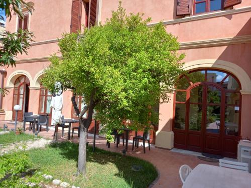 a tree in front of a building with tables and chairs at Oasi Ottocento in Quartu SantʼElena