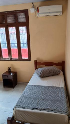 a bedroom with a bed and two windows at Quarto suite master para 3 pessoas in Belém
