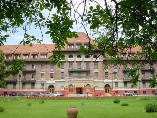 un grand bâtiment avec un champ vert en face dans l'établissement Hotel Triumf, à Bucarest
