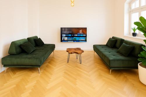 two green couches and a table in a living room at Denkmalgeschützte große Boheme Altbauwohnung in Citylage in Landshut