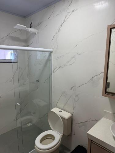 a bathroom with a toilet and a glass shower at House in the center of Bauneario Picarras in Piçarras