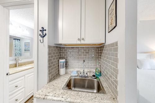 Una cocina con fregadero y gabinetes blancos. en Pirates Bay B102, en Fort Walton Beach