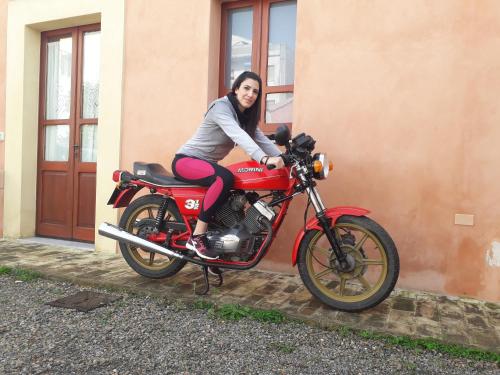 a woman is sitting on a red motorcycle at Oasi Ottocento in Quartu SantʼElena