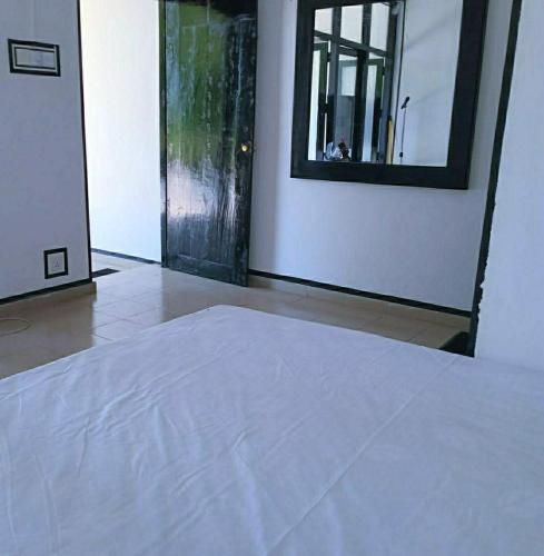 une chambre avec un lit blanc et un miroir dans l'établissement Malindu Restaurant & Rooms, à Katunayake
