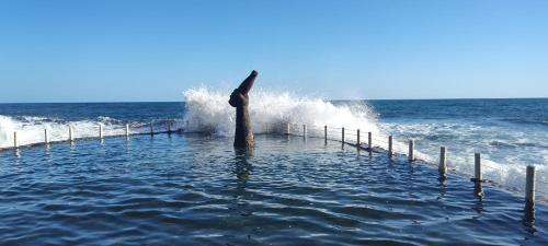 a wave crashing on a pier in the ocean at Cadejo Brewing Company El Sunzal in Tamanique