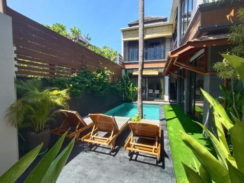 an outdoor patio with chairs and a swimming pool at Villa CUCU - Legian - 3 Bedroom in Legian