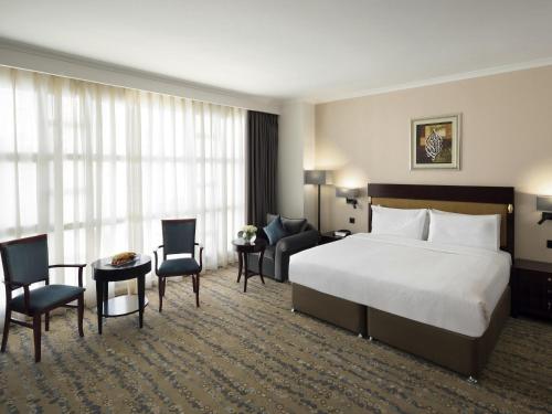 a hotel room with a bed and a desk and chairs at Anwar Al Madinah Mövenpick in Al Madinah