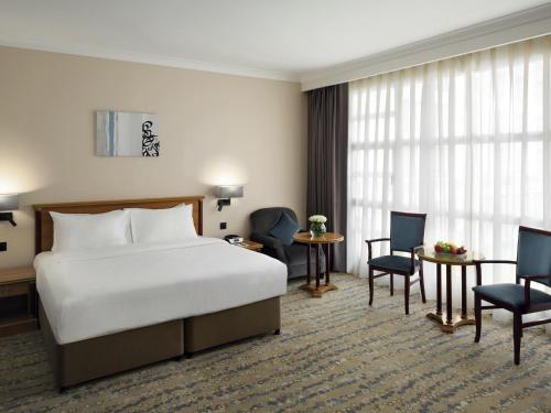a hotel room with a bed and a desk and chairs at Anwar Al Madinah Mövenpick in Al Madinah