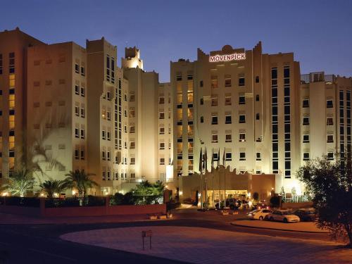 a large building with a sign on it at night at Mövenpick Hotel Doha in Doha
