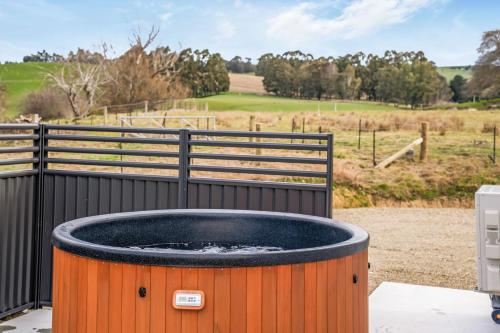 a hot tub with a fence and a field at Bellamy Station - Luxury on the Clutha Gold Trail in Evans Flat
