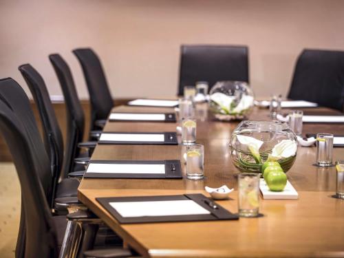 a long wooden table with black chairs around it at Mövenpick Hotel Doha in Doha
