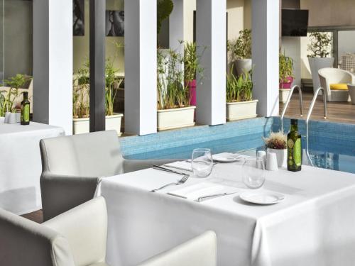 a white table and chairs in a restaurant at Mövenpick Hotel Casablanca in Casablanca