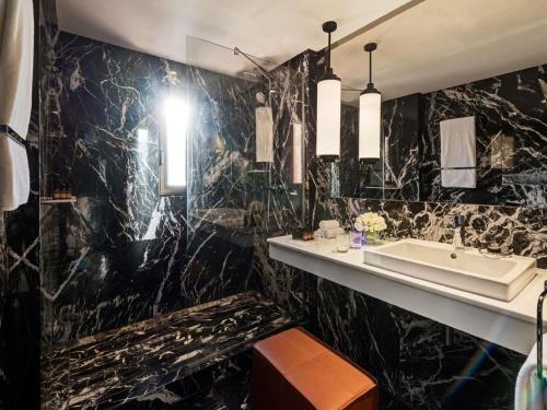 a bathroom with a sink and black marble walls at Mövenpick Hotel Mansour Eddahbi Marrakech in Marrakech