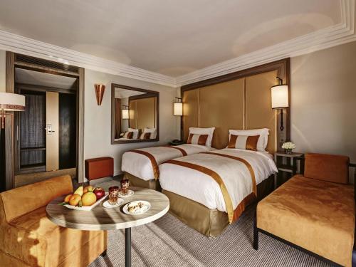 a hotel room with a large bed and a table at Mövenpick Hotel Mansour Eddahbi Marrakech in Marrakech