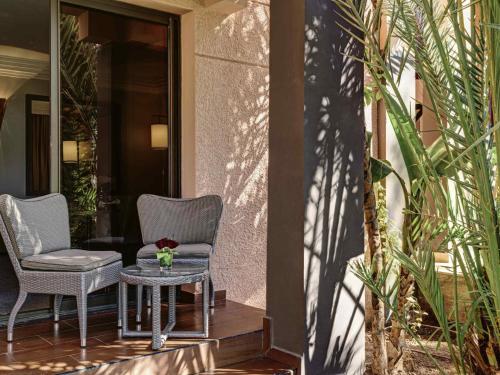 two chairs and a table on a porch at Mövenpick Hotel Mansour Eddahbi Marrakech in Marrakech