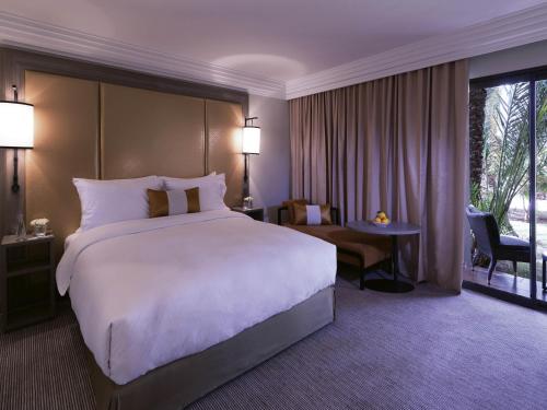 a hotel room with a large bed and a desk at Mövenpick Hotel Mansour Eddahbi Marrakech in Marrakech
