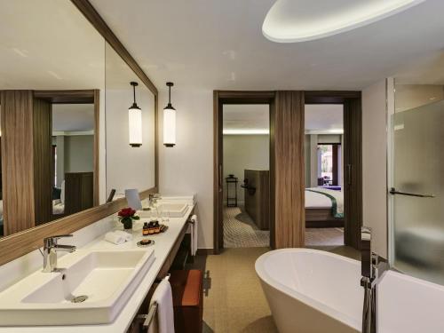 a bathroom with two sinks and a bath tub at Mövenpick Hotel Mansour Eddahbi Marrakech in Marrakech