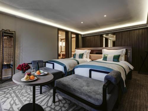 a hotel room with two beds and a table at Mövenpick Hotel Mansour Eddahbi Marrakech in Marrakech