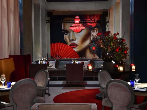 a dining room with a large painting of a woman at Mövenpick Hotel Mansour Eddahbi Marrakech in Marrakech