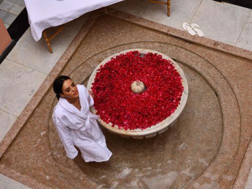 a woman standing next to a large display of red flowers at Mövenpick Hotel Mansour Eddahbi Marrakech in Marrakech