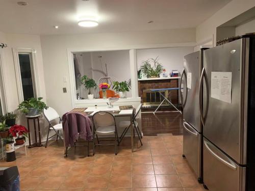a kitchen with a table and a stainless steel refrigerator at Private comfortable M1 bedroom in Mississauga