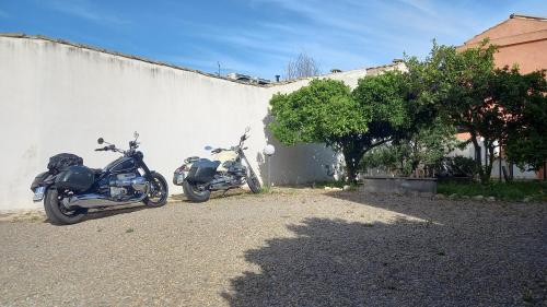 two motorcycles parked next to a white wall at B&B Antica Villa in Quartu SantʼElena