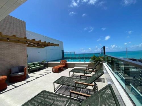 a balcony with tables and chairs and the ocean at Smart Stay Experience in Maceió