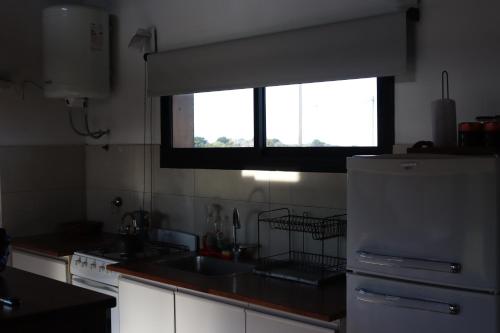 a kitchen with a white refrigerator and a window at Lomada chapadmalal in Chapadmalal
