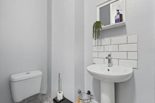 a white bathroom with a toilet and a sink at Lowestoft Seaside Escape by Eason Stays, Free Parking next to Sea Front in Oulton