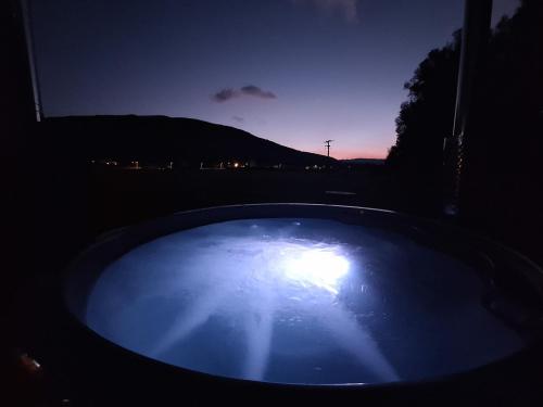 a hot tub in the dark with a sunset in the background at O'Toole's, Plitvice in Korenica