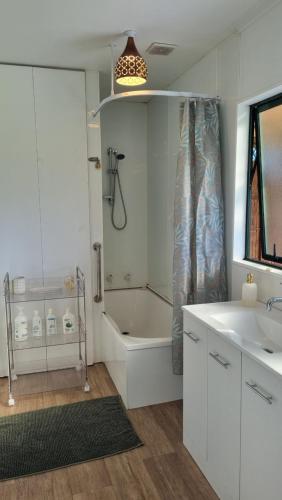 une salle de bain avec une baignoire, une douche et un lavabo dans l'établissement Kereru Cottage , rural B&B, Tauranga, à Whakamarama