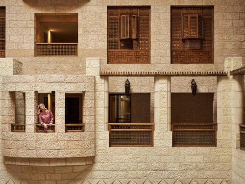 a woman looking out of a window of a building at Mövenpick Resort Petra in Wadi Musa