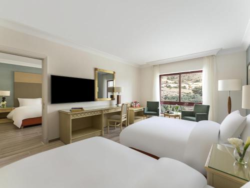 a hotel room with two beds and a desk at Mövenpick Resort Petra in Wadi Musa