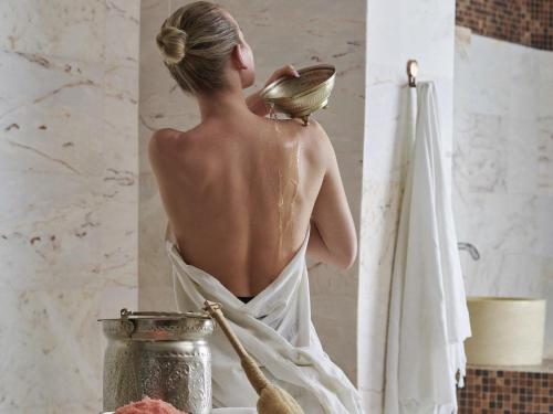 a woman in a bathroom with a bowl on her shoulder at Mövenpick Resort Petra in Wadi Musa