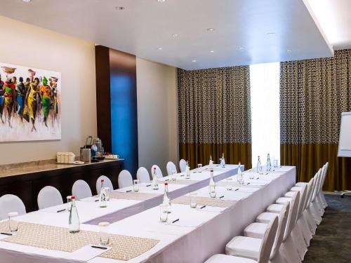 a large meeting room with white tables and white chairs at Mövenpick Ambassador Hotel Accra in Accra