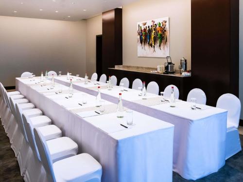 a row of tables and white chairs in a room at Mövenpick Ambassador Hotel Accra in Accra