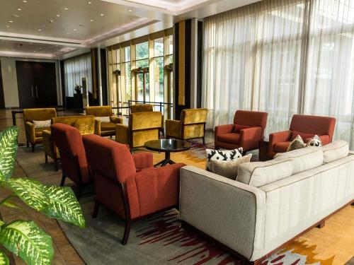 a lobby with a couch and chairs and a table at Mövenpick Ambassador Hotel Accra in Accra