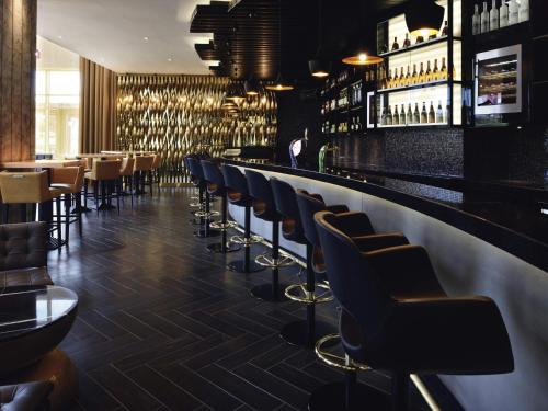 a bar with a row of chairs and wine bottles at Mövenpick Ambassador Hotel Accra in Accra