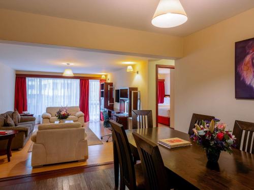 a living room with a table and a dining room at Mövenpick Hotel & Residences Nairobi in Nairobi