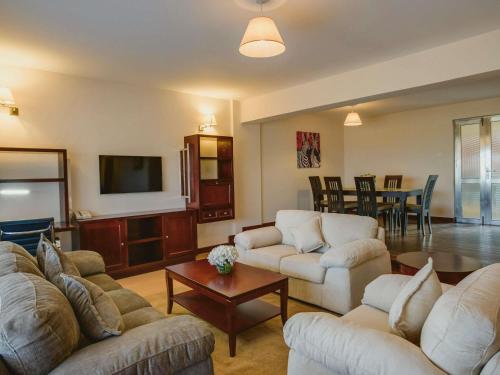 a living room with couches and a flat screen tv at Mövenpick Hotel & Residences Nairobi in Nairobi